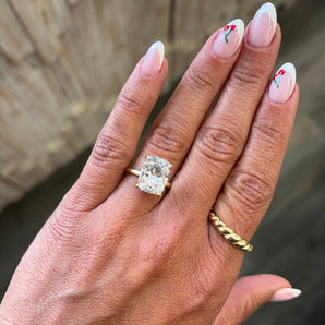 A close-up of a hand wearing a custom-made 14k gold elongated cushion lab grown diamond solitaire engagement ring