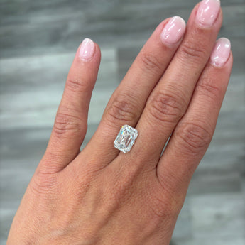 A loose 4.00ct cushion crisscut lab grown diamond resting on the ring finger of a hand