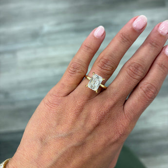 A close-up of a hand wearing a custom-made 14k gold 4.00 carat crisscut cushion lab grown diamond solitaire engagement ring
