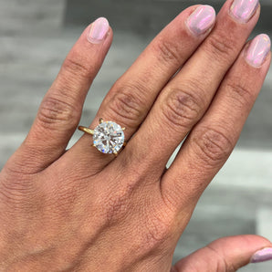 A close-up of a hand wearing a custom-made 14k gold round lab grown diamond solitaire engagement ring 