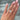 A loose 4.00ct cushion crisscut lab grown diamond resting on the ring finger of a hand